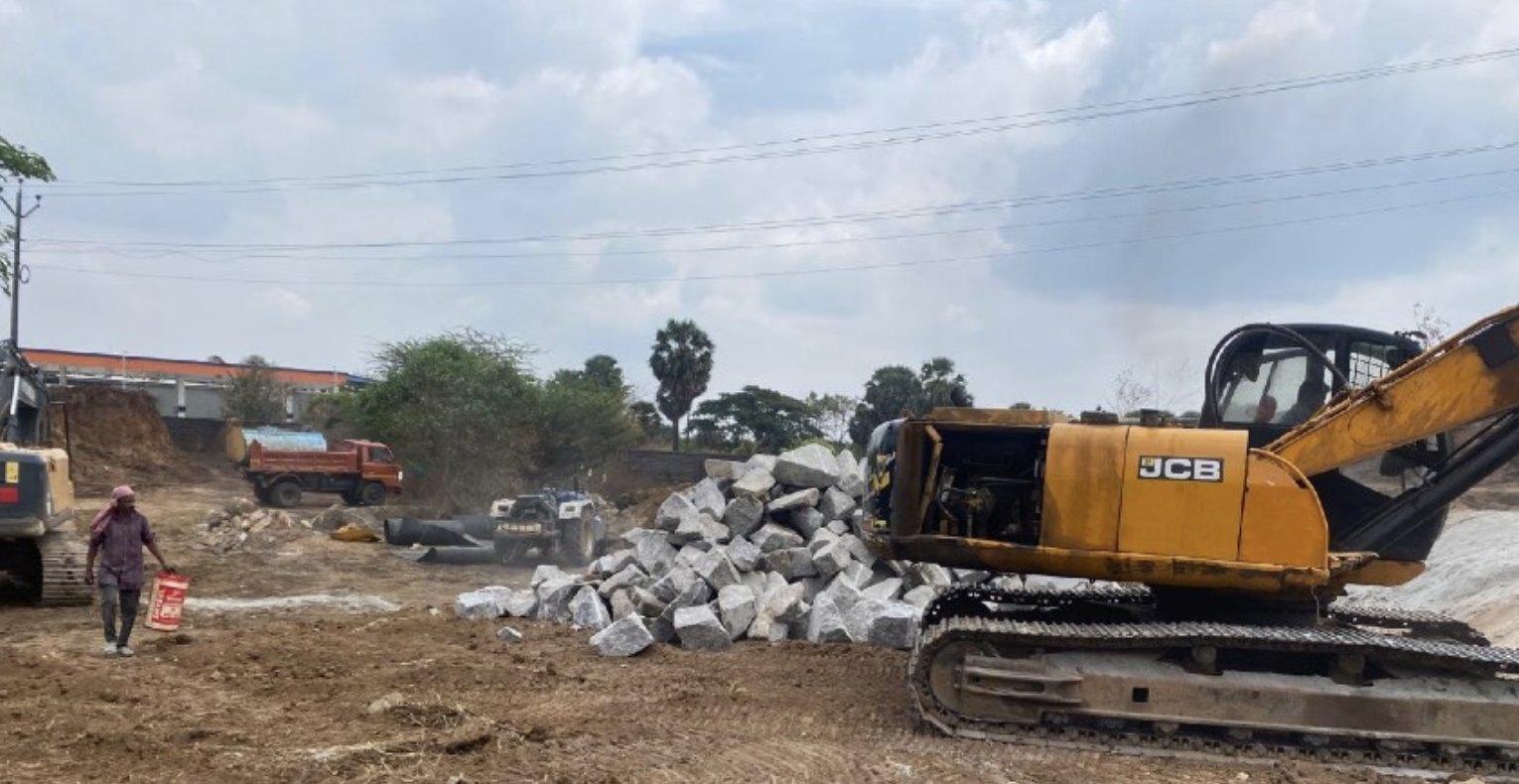 Excavator working near rock and earth at the project site